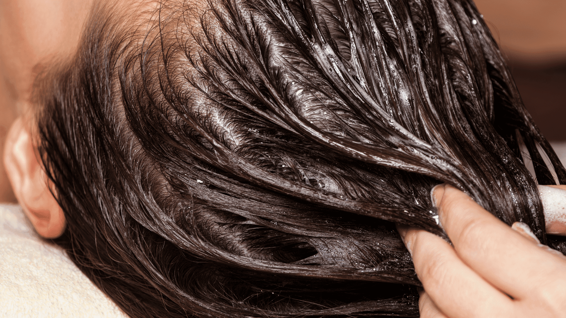 Hair undergoing a conditioning treatment, being massaged with a rich, creamy product.