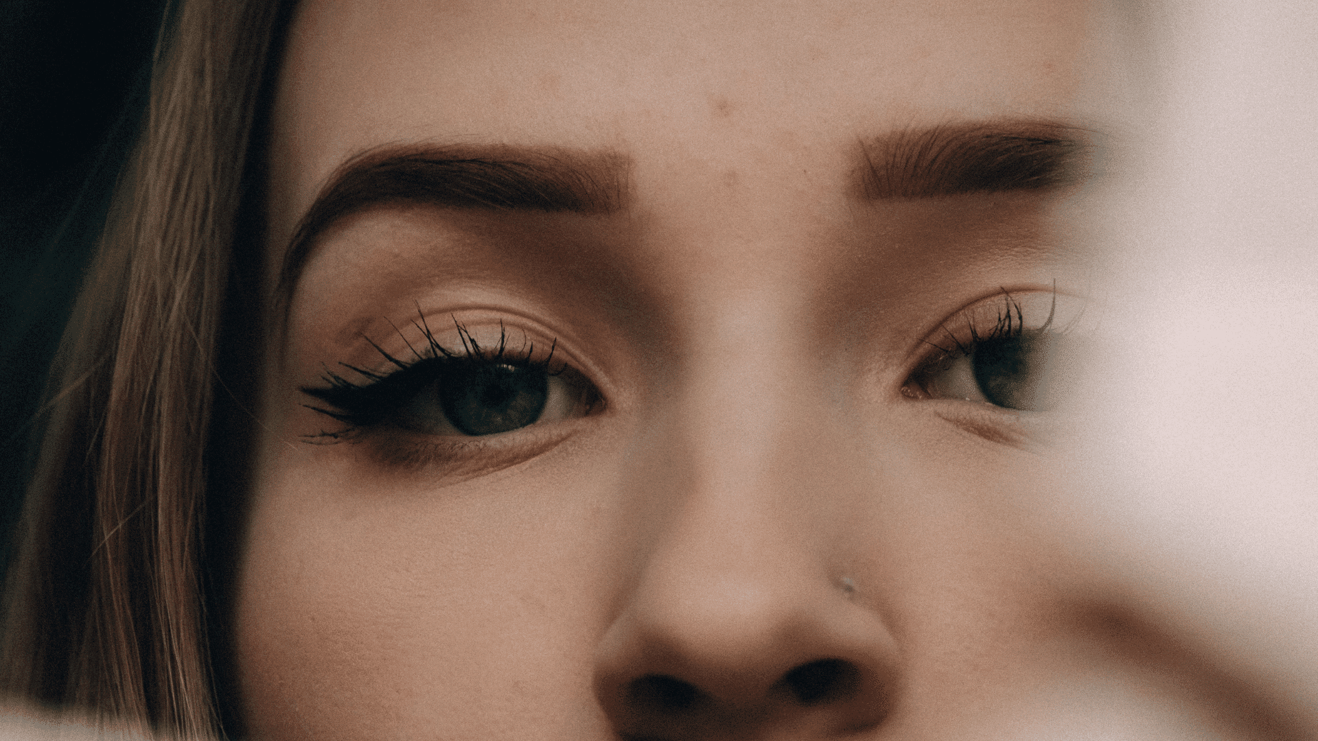Close-up of a woman's eyes with bold eyebrows and makeup.