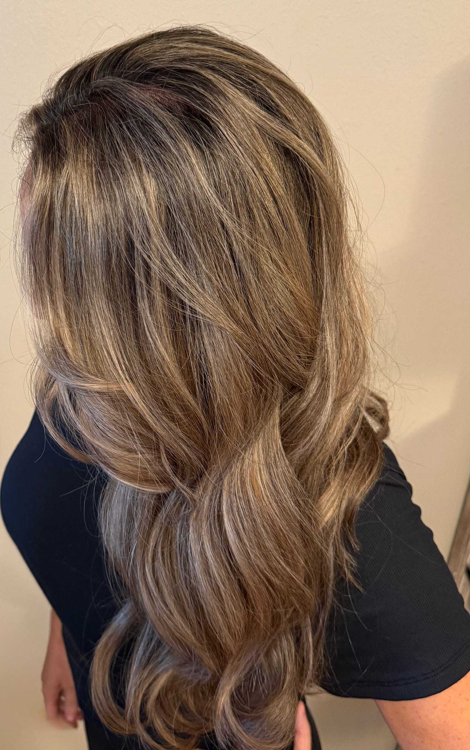 Wavy light brown hair with highlights, styled elegantly.