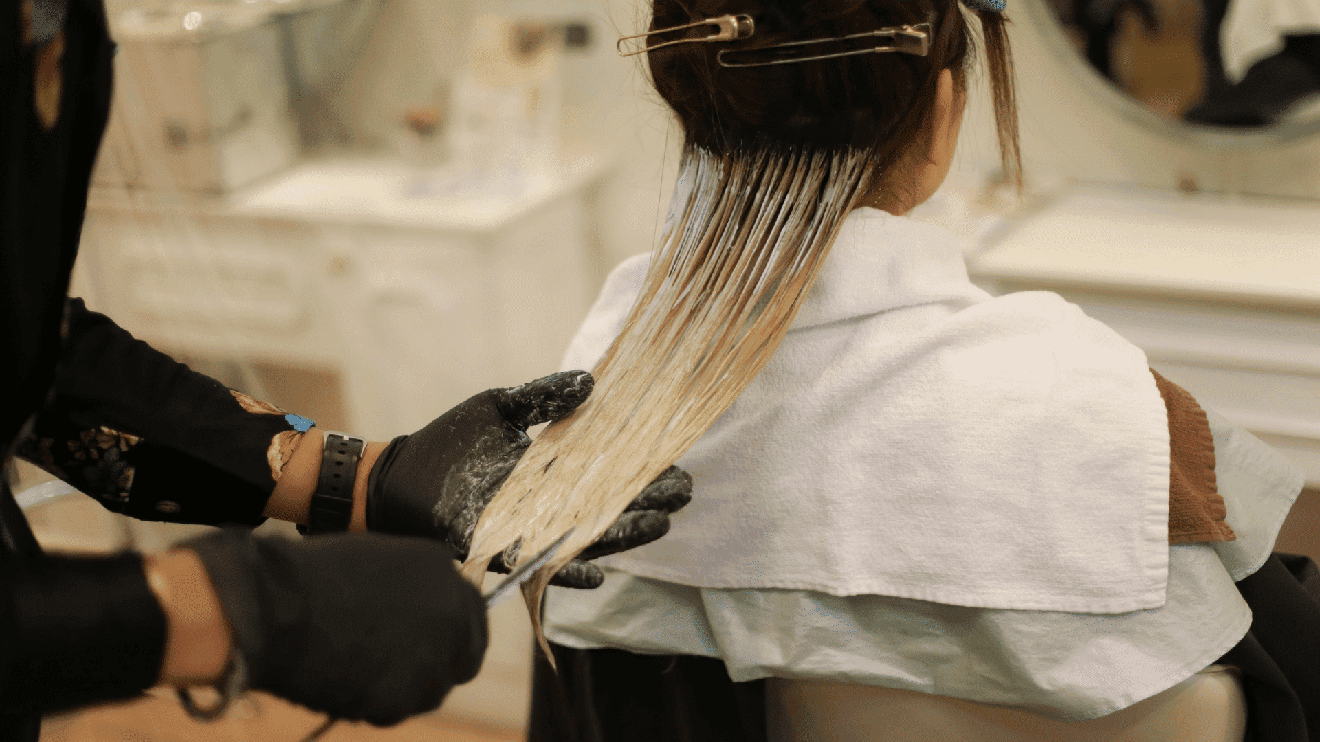 Hairdresser applying dye to woman's hair in salon.