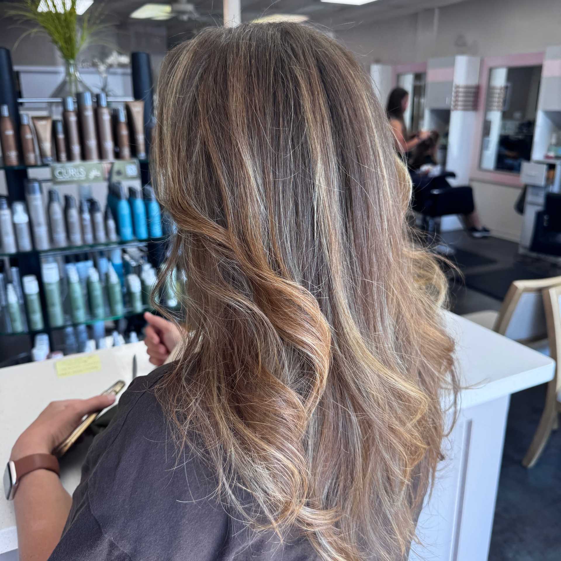 Hair salon interior with a focus on styled, wavy hair near a product display.