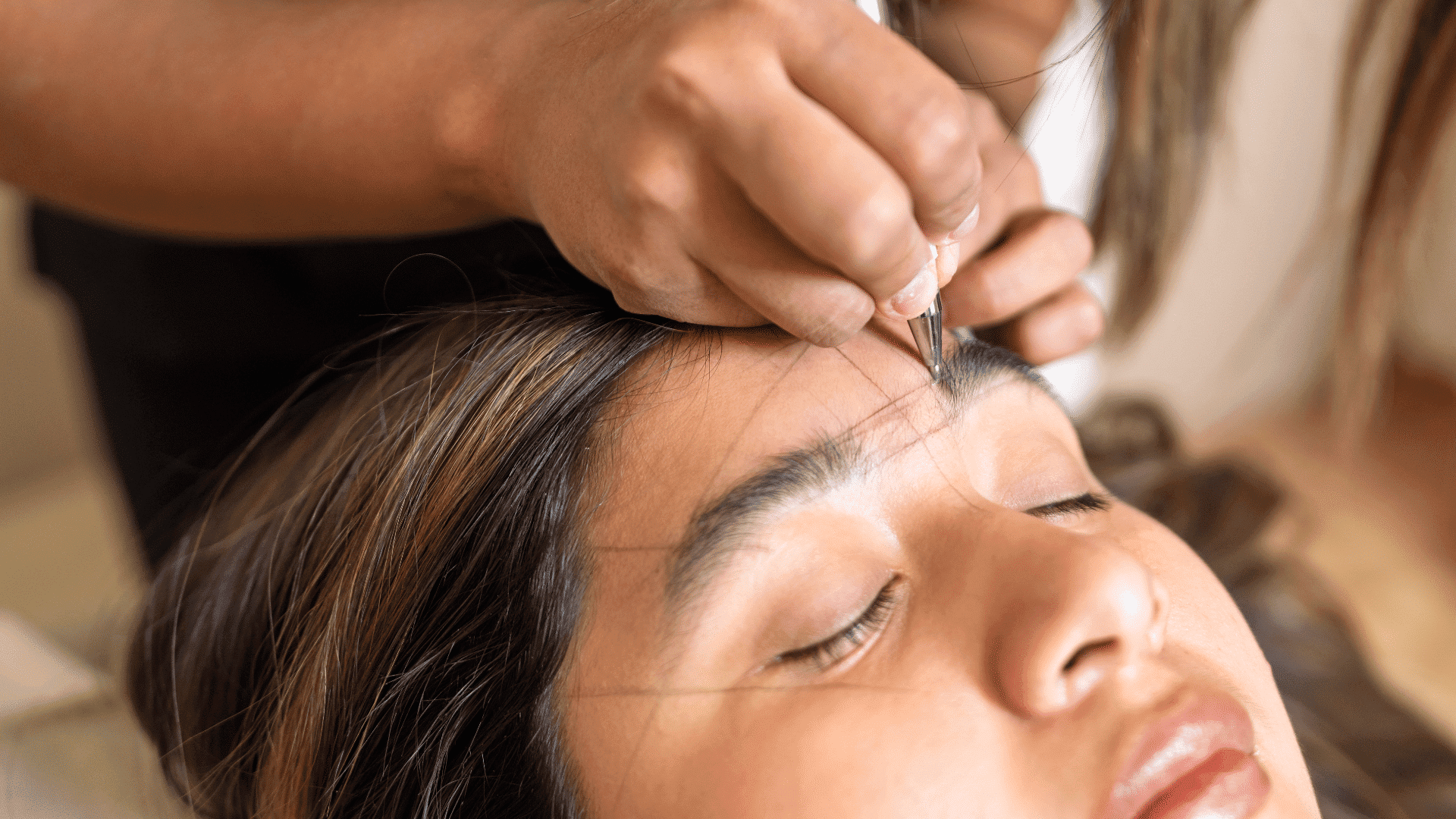 Eyebrow threading procedure close-up on serene woman's face.