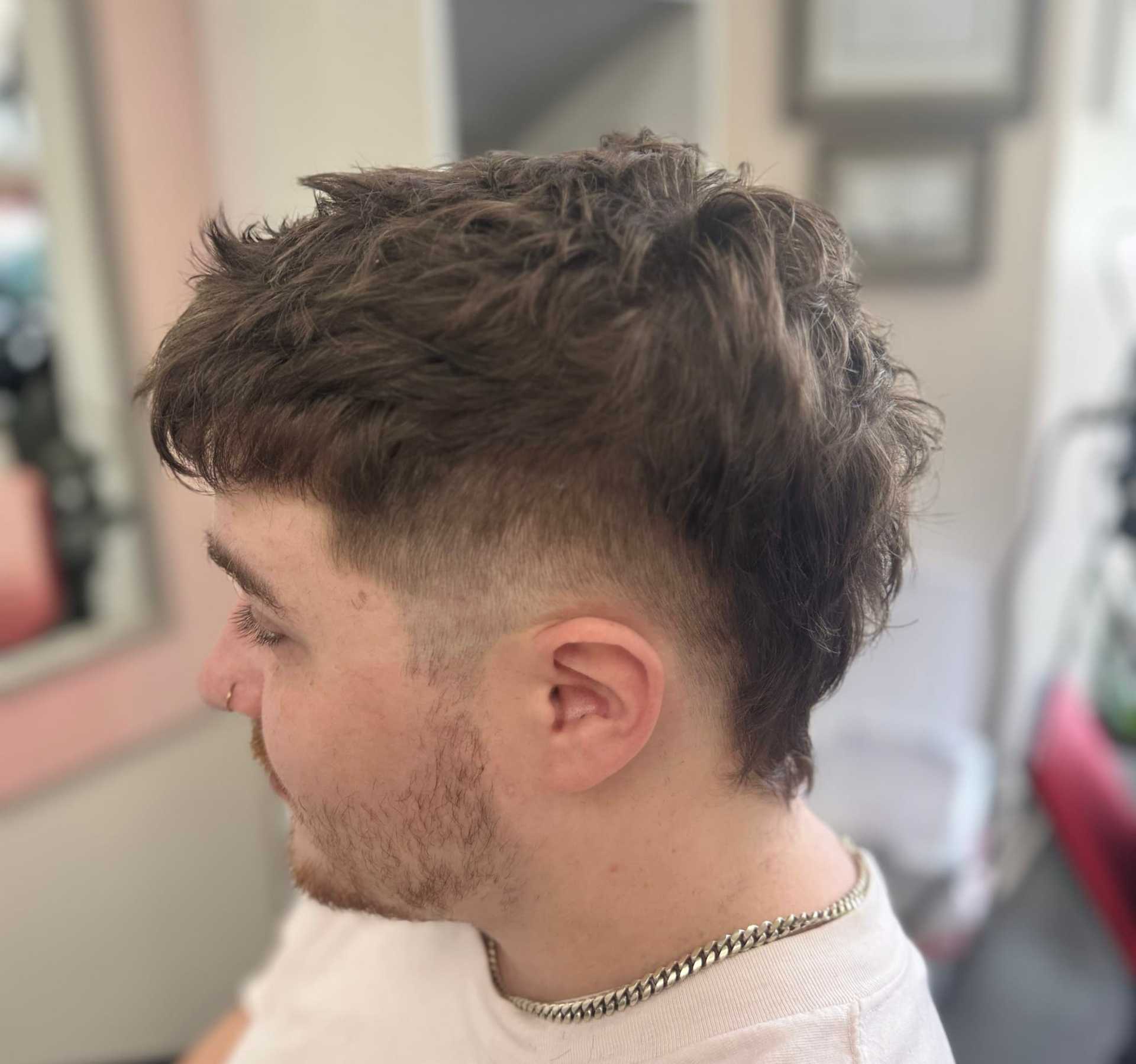 Young person with a modern mullet hairstyle, featuring shaved sides and longer textured top.