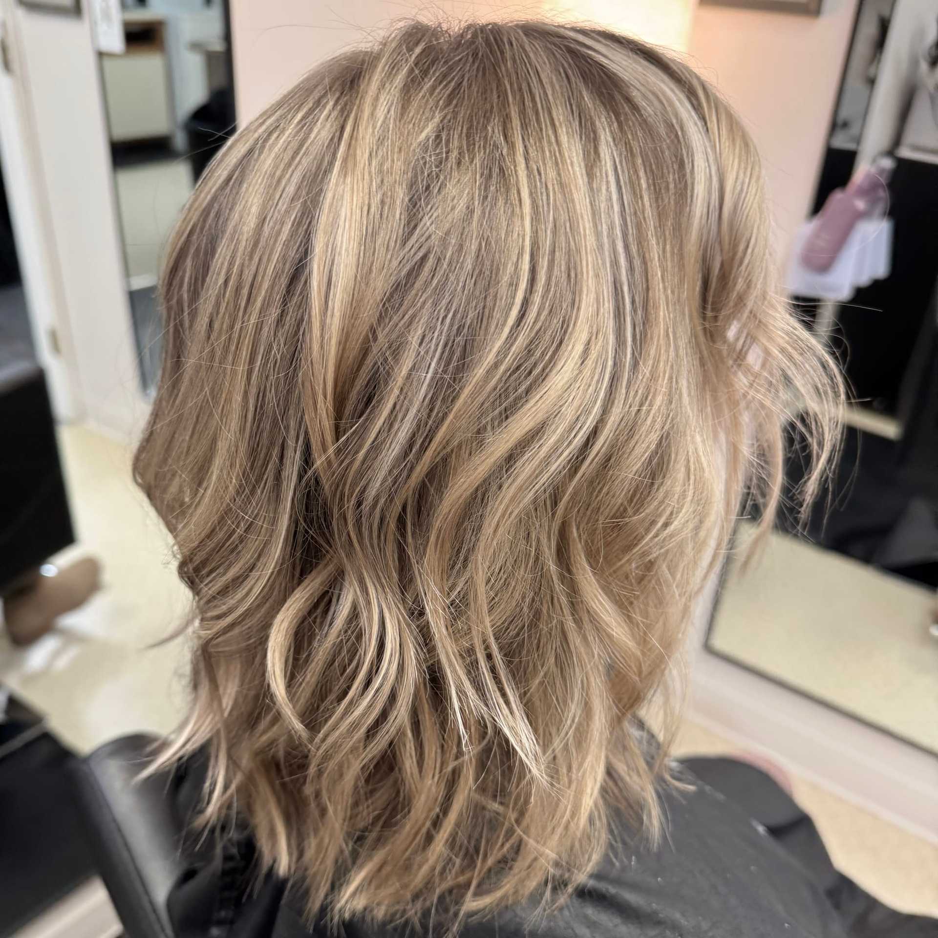 Wavy blonde hair with highlights styled in a layered shoulder-length cut.