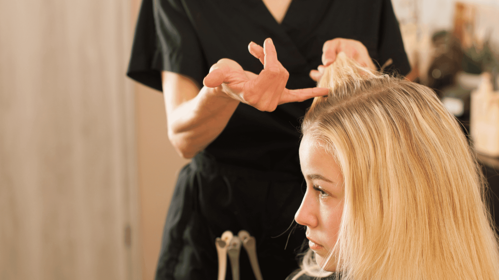 Hairstylist working on a woman's blonde hair in a salon setting.
