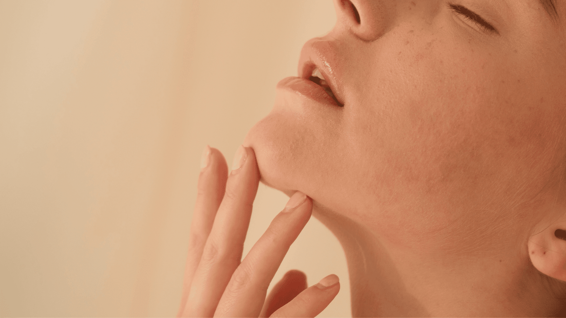 Close-up of a woman's face with closed eyes, focusing on her chin and lips.