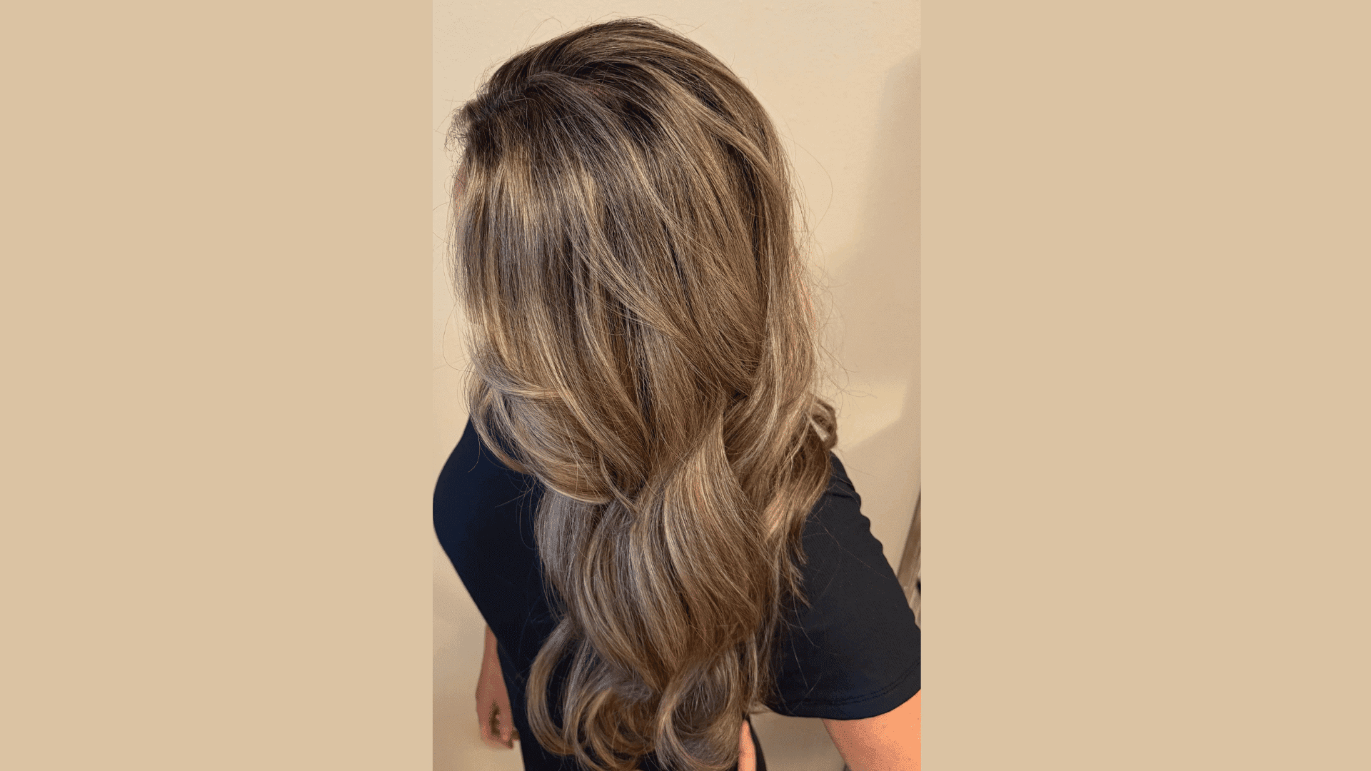 Elegant wavy hairstyle with highlights on a woman in a black shirt, shown from the back.