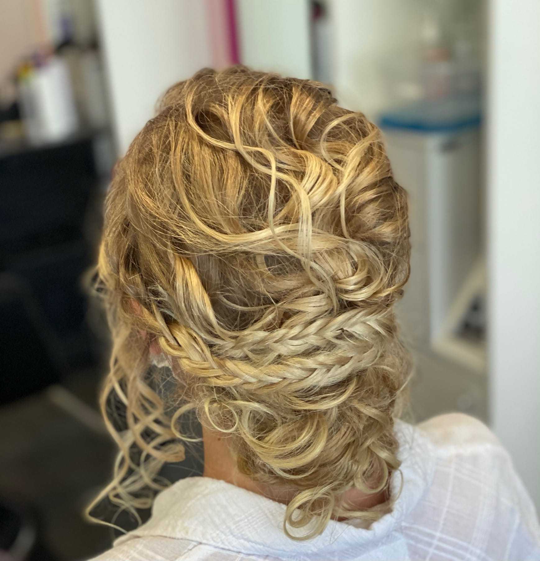 Elegant braided blonde updo hairstyle with curls.