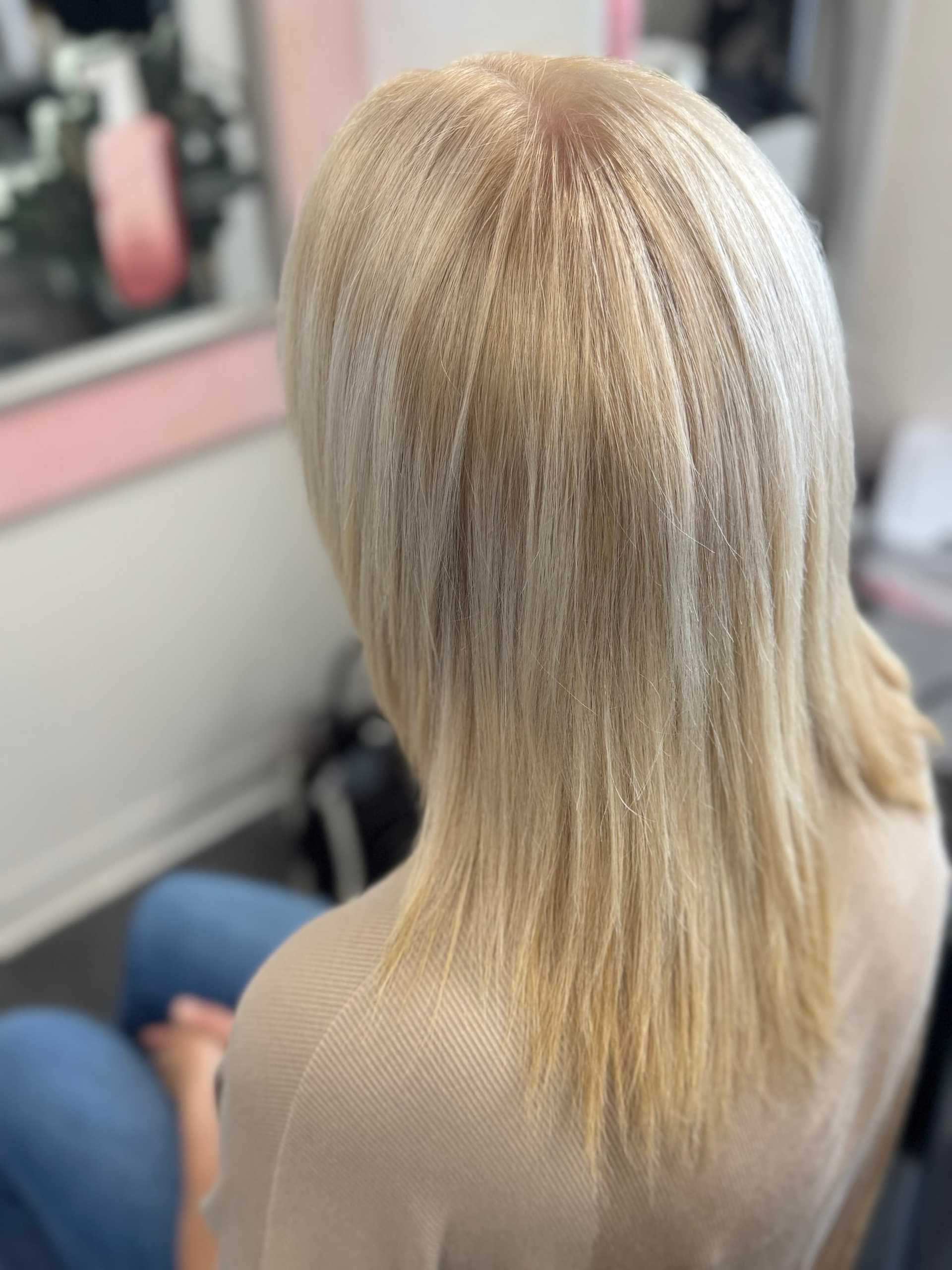 Blonde straight hair from the back, styled in a salon setting.