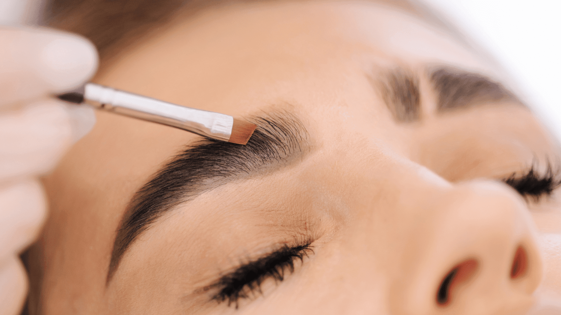 Eyebrow being carefully shaped with a brush during a beauty treatment.