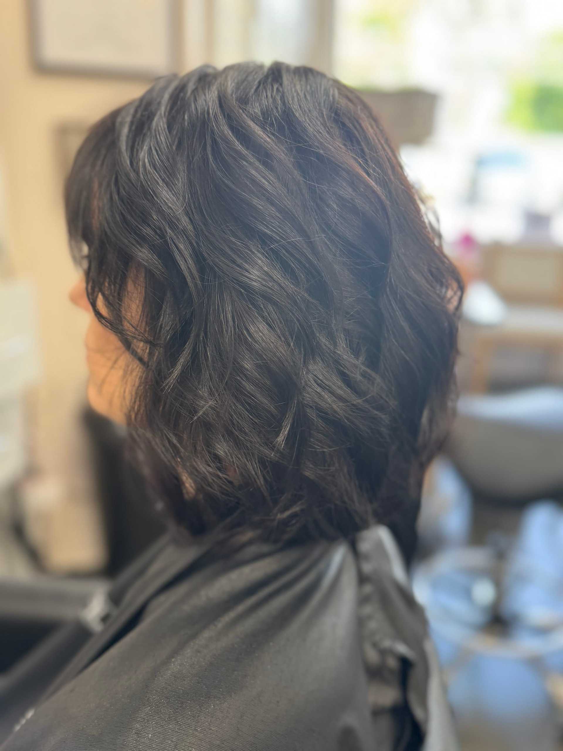 Wavy, shoulder-length dark hair styled in a salon setting.